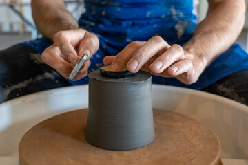 Man trimming pot with tools on the wheel. High quality photo