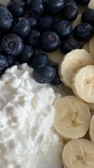 Bowl of cottage cheese topped with fresh blueberries and banana slices.
