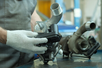 Car service. The car mechanic performs an external inspection of the new turbine before installing...