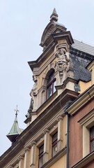Fototapeta premium Facade of a historic building with elegant towers and decorative elements against a winter sky. The atmosphere of an old town.