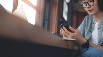 Casual business woman using mobile phone and working on laptop computer at coffee shop. Female freelancer online working, using smartphone and laptop, surfing the internet, work at cafe, close up