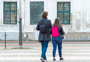 Back view of casual young couple with a backpack on the back walking in the city. Rear view of a...