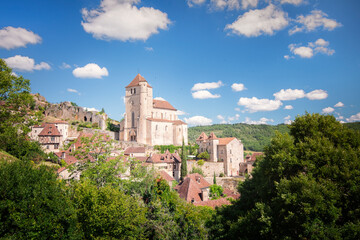 Obraz premium Village medievale et eglise au milieu de la vegetation en été sous un beau ciel bleu, le village medievale de Saint Cirq Lapopie en France dans le Quercy