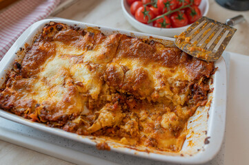 Homemade lasagna with mozzarella cheese crust in a baking dish on kitchen counter