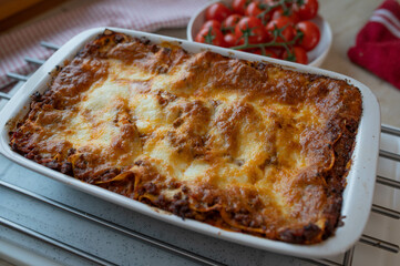Homemade lasagna with mozzarella cheese crust in a baking dish on kitchen counter