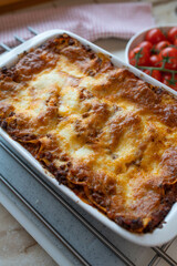 Homemade lasagna with mozzarella cheese crust in a baking dish on kitchen counter