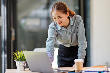 Asian businesswoman work on laptop computer at the office with calculator document on desk, doing planning analyzing the financial report, business plan investment, finance analysis concept.
