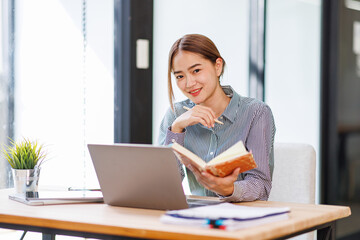 Asian businesswoman work on laptop computer at the office with calculator document on desk, doing planning analyzing the financial report, business plan investment, finance analysis concept.
