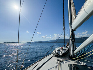 Sailing across calm waters under a bright sun in a picturesque coastal landscape