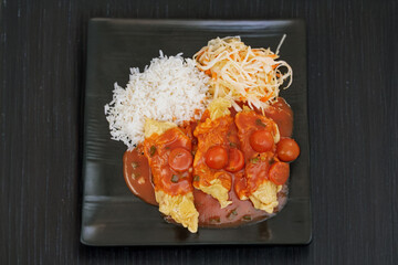 Oriental dish: crispy panko-coated chicken with tomato sauce, salad and rice on a plate stands on the table.