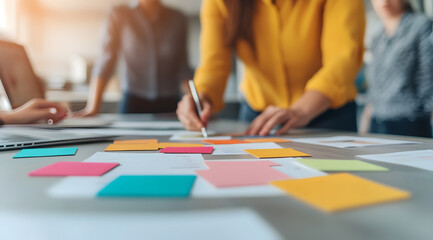 Obraz premium A collaborative workspace with people brainstorming and organizing ideas using colorful sticky notes on a table.