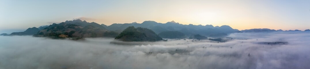 Panorama of sunrise illuminating mountains above a soft sea of clouds in thailand. Top view above the clouds.