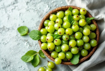 Top view a bowl filled with fresh green gooseberries, with a few leaves visible