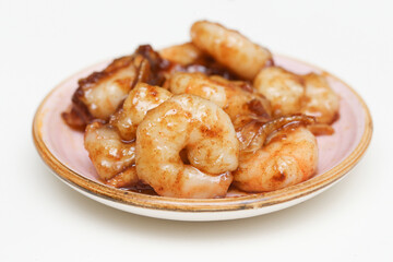 Shrimps on a small plate. Seafood snack with a sweet touch. Honey chili shrimp background. Crispy and delicious food isolated on a white background. Fried prawns dinner meal.