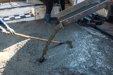 Construction worker working with wet cent pouring from pipe in home improvement site