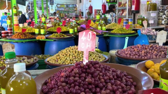 a vibrant display of seasoned chickpeas and olives, garnished with herbs, likely at a market or food stall. The colorful presentation and variety of ingredient