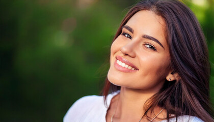 Fototapeta premium Portrait of young smiling woman face partially covered with flying hair in windy day standing at mountain - carefree woman 