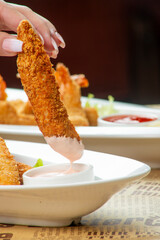 Crispy chicken tender dipped in sauce at a casual dining restaurant