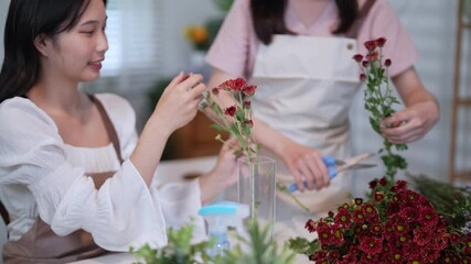 Two florists work together to arrange flowers in a vase, creating a beautiful floral display in a bright and cozy shop