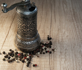 Spice grinder and peppercorns close up. Pepper mill with pepper mix on a wooden table.