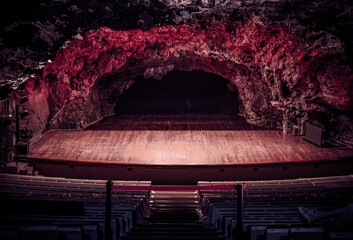 Underground Cave Theater with Wooden Stage and Dramatic Lighting
