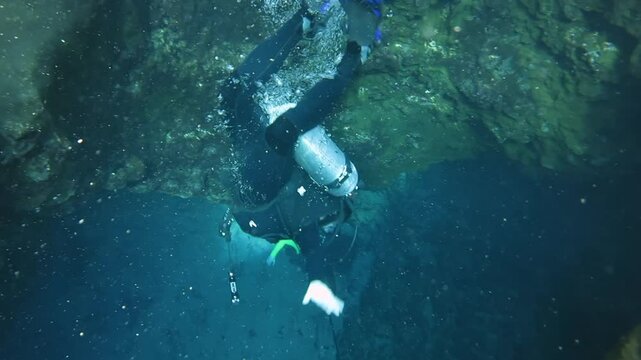 Underwater view of diver diving into underwater cave in blue hole in Florida.