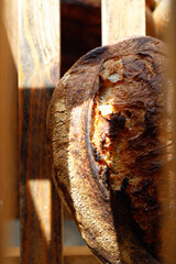 Loaf of crusty sourdough bread on wooden bakery shelf