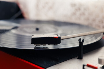 Vinyl record spinning on a turntable with a stylus in a cozy indoor setting during the afternoon