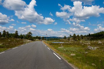 Scenic highway surrounded by lush landscapes and vibrant clouds in the countryside during daylight hours.