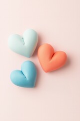 Fototapeta premium Valentine pink background, Three colorful heart-shaped objects in pastel shades, arranged on a soft pink background, evoke feelings of love and warmth.