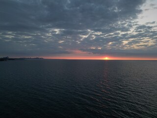 Sunrise Over Lake Ontario with Toronto Skyline Silhouette Under Dramatic Clouds
