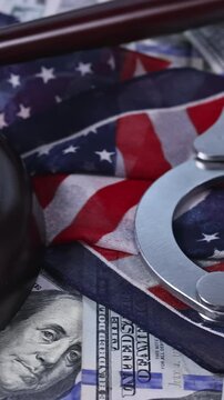 Justice gavel rests of cash with handcuffs an American flag, symbolizing law, justice system concerns