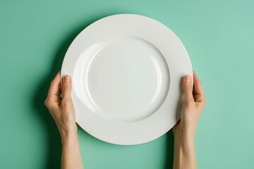 A person is holding a white plate with a green background