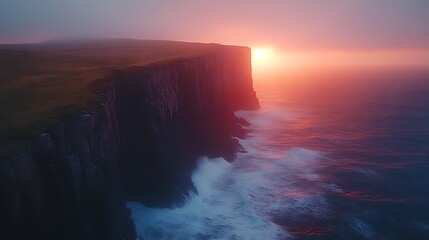 Dramatic sunset over coastal cliffs with crashing waves.