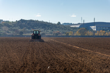 Fototapeta premium Backlit: Agricultural Tractor in Motion, Plowing the Field.