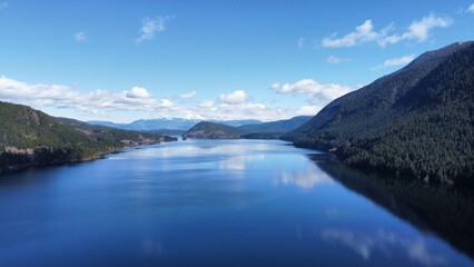 Fototapeta premium Aerial View of Serene Lake and Forested Mountains on Vancouver Island Under a Clear Blue Sky