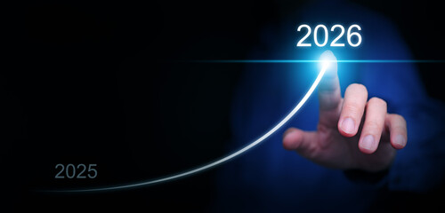 Happy new year. A businessman draws a line rising up, from 2025 to  2026, representing aimed...