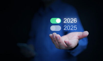 Happy new year 2026. A businessman holds an on-switch of 2026 toggle button to start and welcome the new coming year.