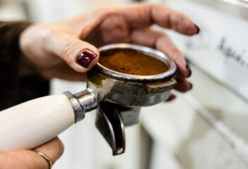 Woman is hands adjusting coffee grounds in portafilter.