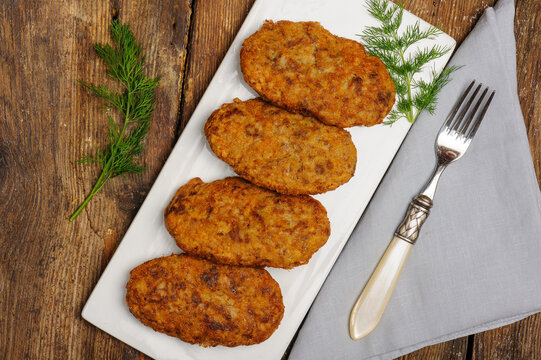 Top view photo of  fried rice and meat patties, a popular traditional Turkish food also known as lady's thighs or kadın budu k&ouml;fte  on vintage wooden table with fresh dill, linen napkin