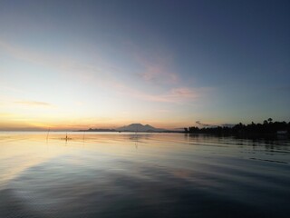 Tranquil Sunrise Over Calm Coastal Waters with Distant Mountains in the Philippines