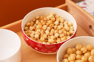 Crispy bread croutons for soup served in small bowls on a wooden tray. Golden fried bread cubes with a rich, crunchy texture. Perfect as a tasty addition to soups and salads.  Soup puffs pearls.