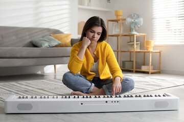 Upset woman near synthesizer on floor at home