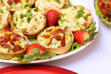 Avocado paste tartlets topped with guacamole and crispy chorizo chips. Savory party snack combining creamy avocado spread with the smoky crunch of chorizo, perfect for gatherings and celebrations.