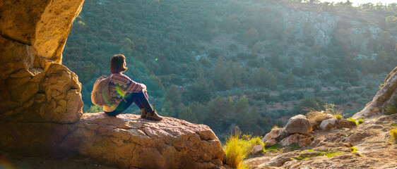 happy woman in the mountains. girl resting sitting on a stone in the mountains. trekking and...