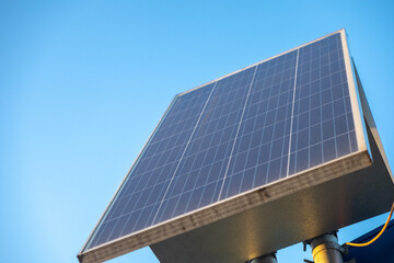 solar panel against a clear blue sky, mounted on a metal structure, capturing sunlight for renewable energy generation
