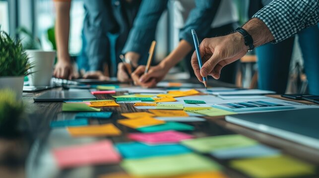 A dynamic group of team members huddled around a table, actively writing ideas on sticky notes, showcasing creativity and collaboration in a friendly work environment.