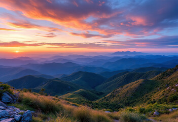 Obraz premium Scenic view of rolling blue mountain ranges against a colorful sunset sky