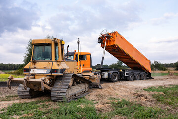Crawler dozer an dump at a construction site in a quarry. Powerful modern equipment for earthworks. Construction site. Heavy bulldozer and dump or lorry at work. Building machines.