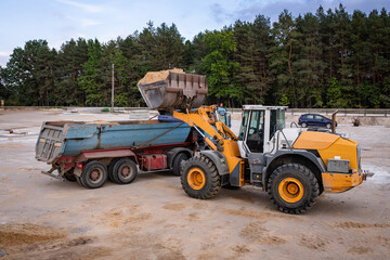 Wheel front loader at a construction site in a quarry. Powerful modern equipment for earthworks. Construction site. Heavy wheel loader at work.
